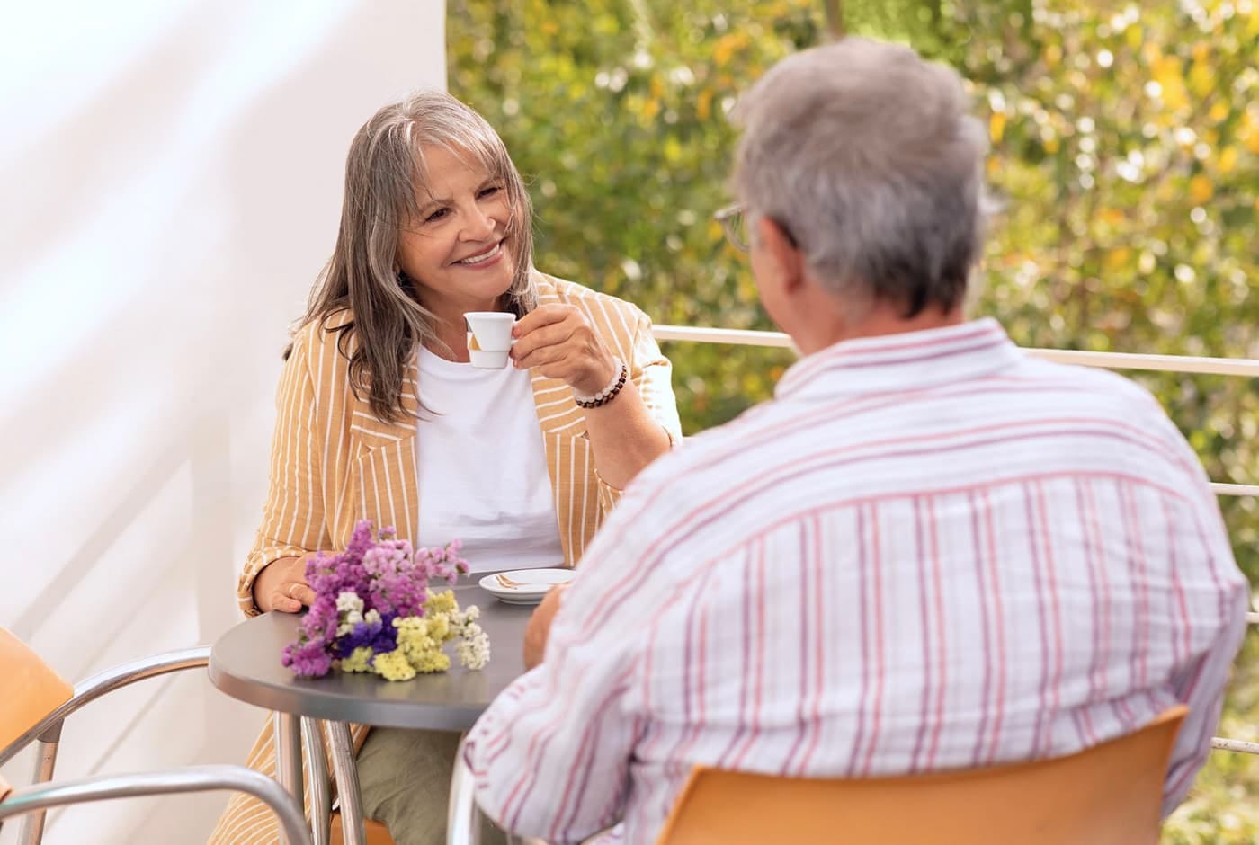 an older couple enjoying afternoon tea in the garden, a bouquet of spring flowers rests on the table