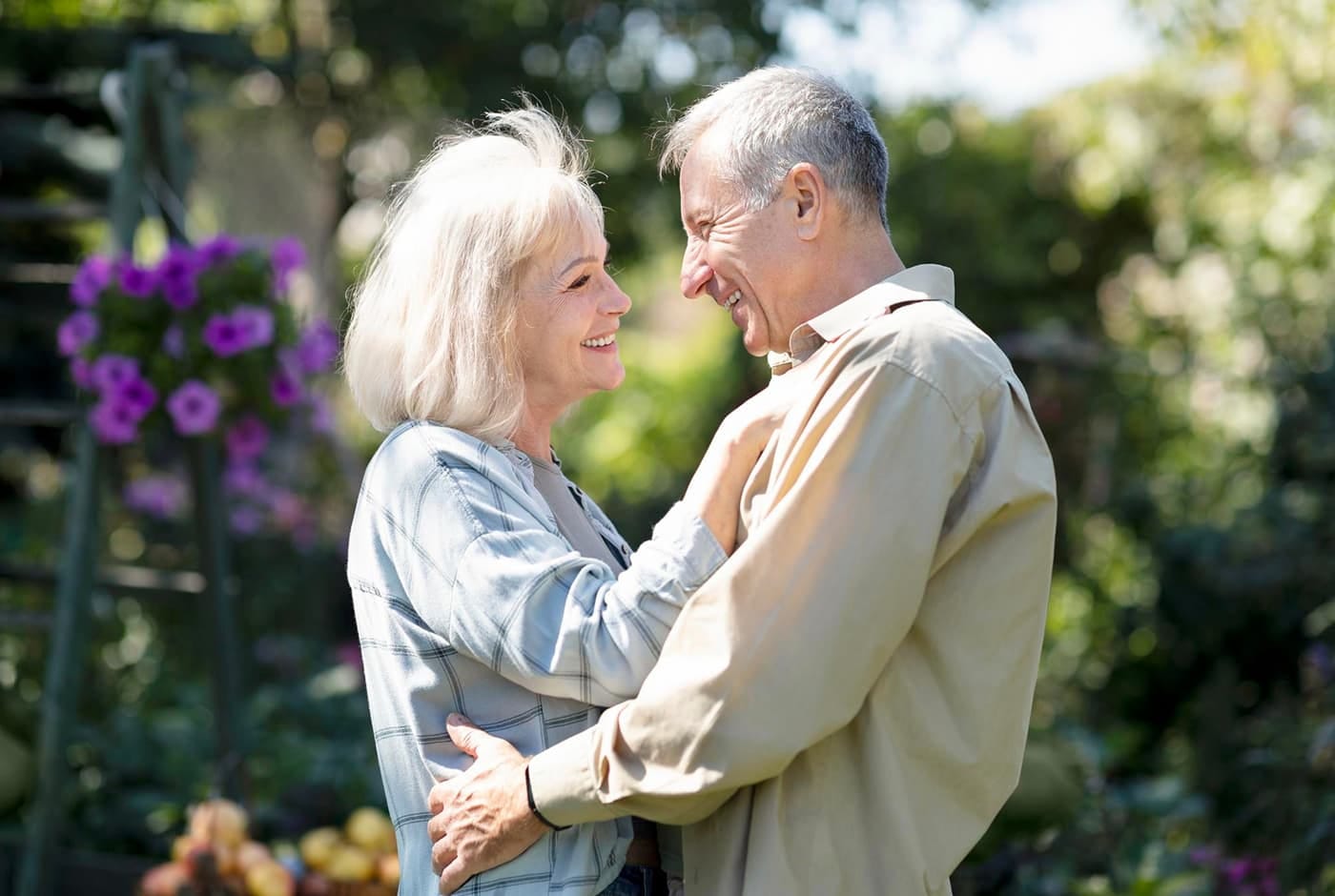 Older couple embracing and smiling at each other outdoors in a garden