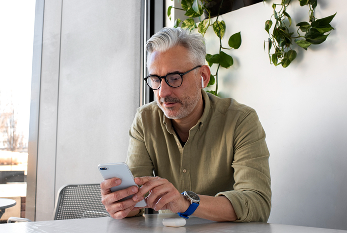 Mature man with glasses using a dating app on his phone